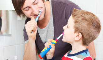 barn och vuxen borstar tänderna