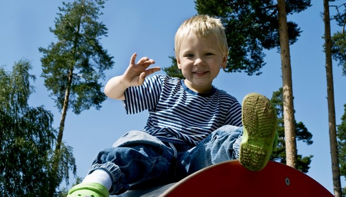En glad pojke som leker i en lekpark