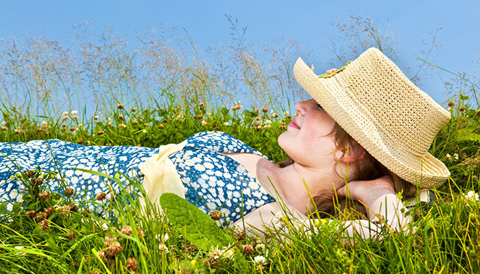 En kvinna ligger på rygg i gräset och har det skönt