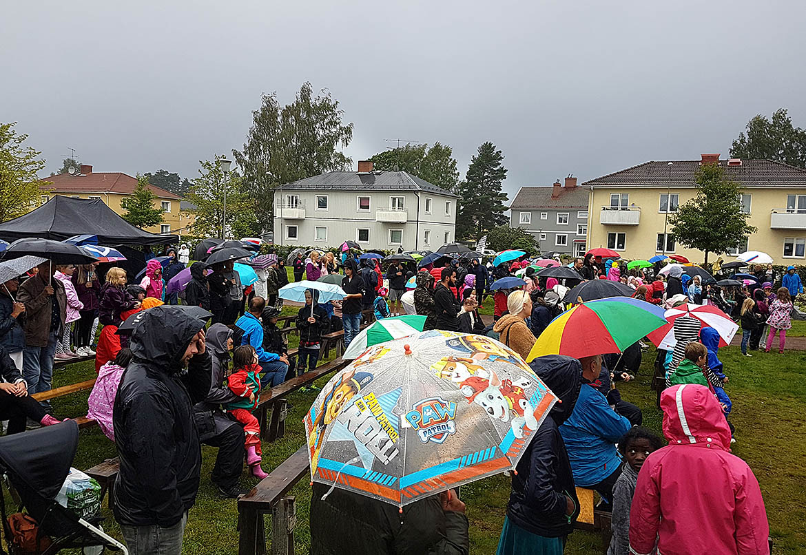Publik med regnkläder och paraplyer
