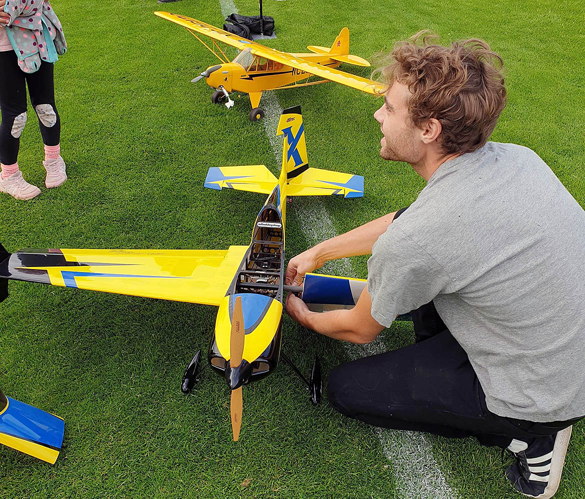 Ung man på gräsmatta med modellflygplan