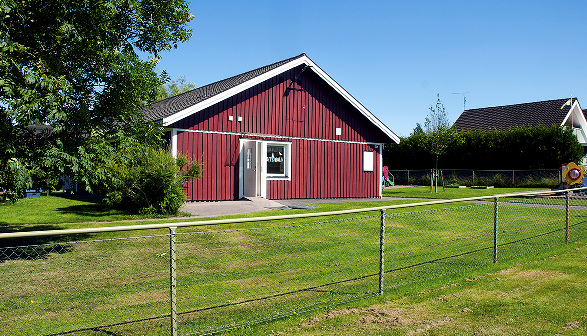 Exteriörbild på röd byggnad (Boda förskola) i sommargrönska