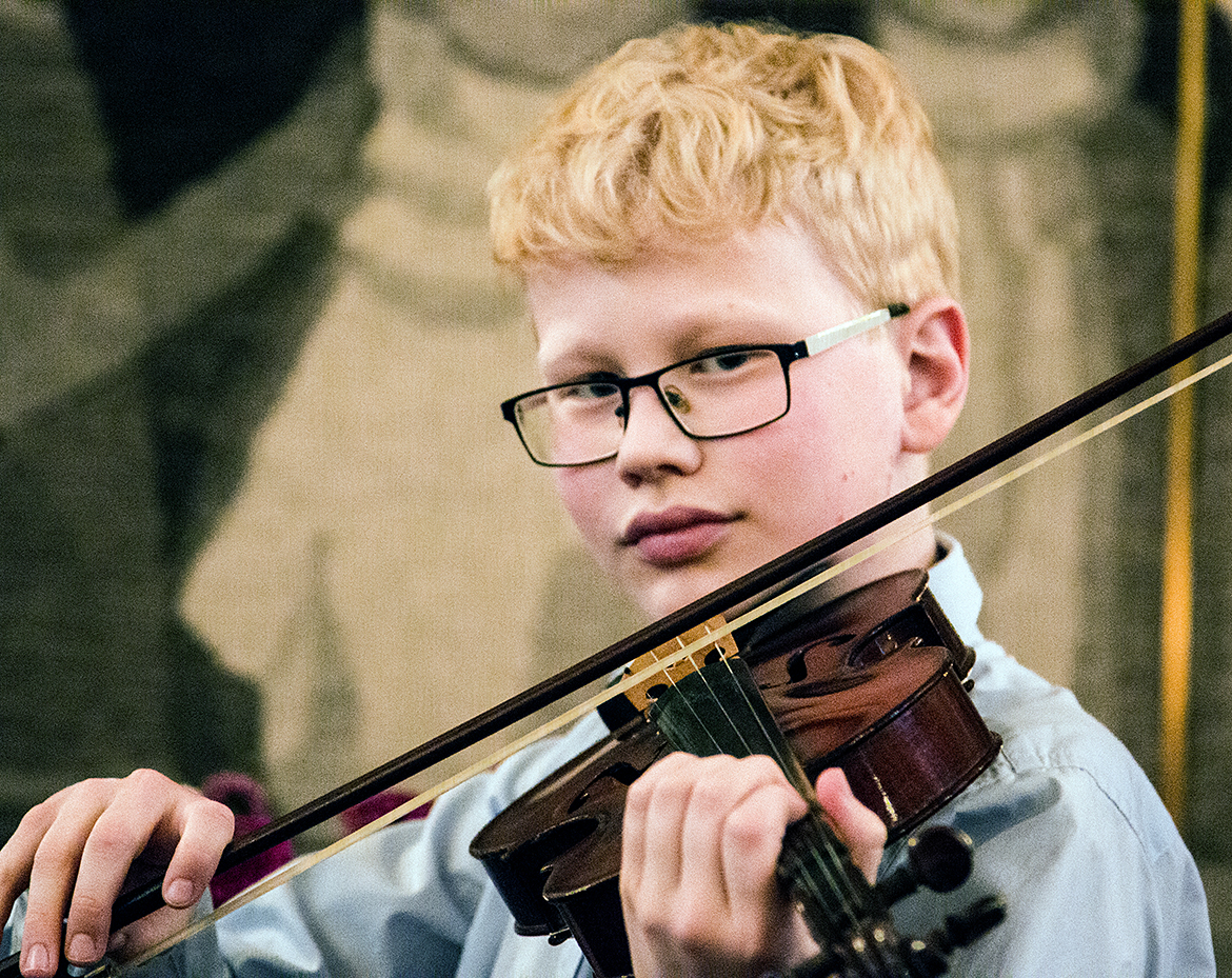 Pojke med glasögon spelar violin