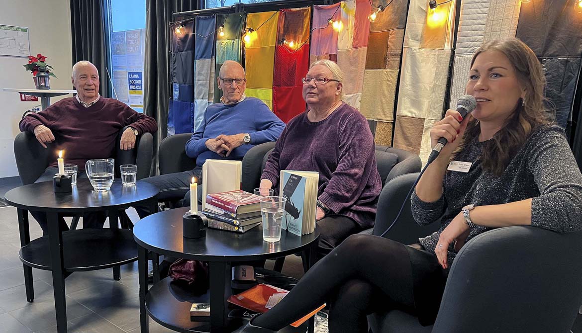 Författarna Berndt Andersson, Henry Nilsson och Anita Andersson sitter på scenen och samtalar med biblioteksassistent Sofia Maier. Färgglatt tyg och lyktor i bakgrunden, levande ljus på borden.