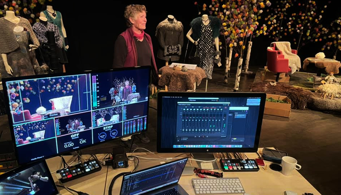 datorer och skärmar med sändningsprogram, i bakgrunden ses kvinna stå bland ullris och skyltdockor med yllekläder